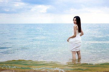 Fototapeta na wymiar Beautiful girl young woman asia standing in water on sandy on the beach at sunset,enjoy summer vacation on the beach.