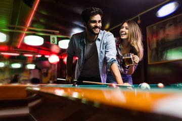 Happy young man playing snooker with his girlfriend. Happy loving couple.