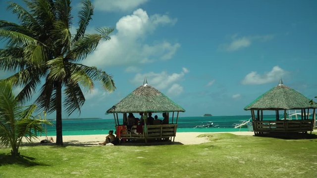 Travel concept: a beautiful beach with bungalows and palm trees near the turquoise water. Summer and travel vacation concept