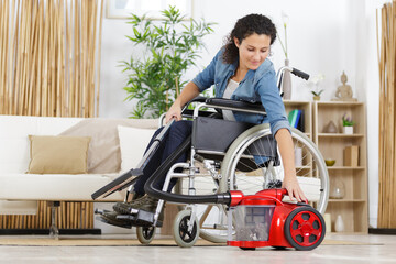 woman on wheelchair with vacuum cleaner vertical