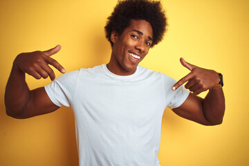 American man with afro hair wearing white t-shirt standing over isolated yellow background looking...