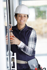 woman builder drilling on the wall