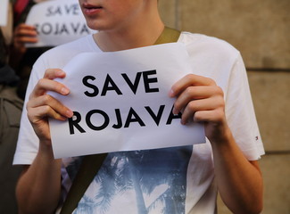 Young man holding white paper with black slogan SAVE ROJAVA, protests against Turkish invasion in northern Syria