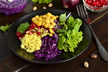 Healthy vegetarian salad. Millet, chickpea, pomegranate seeds, red cabbage, onions, arugula. Buddha bowl.