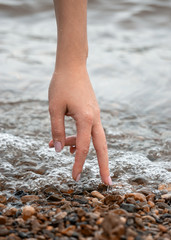 Woman hand touch water on coast