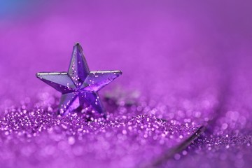 Christmas background.Violet star close-up on a lilac glitter background on a blurry purple...