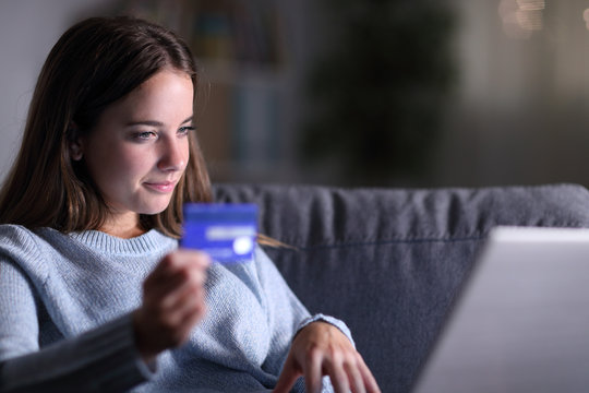 Serious woman using laptop and credit card to buy online