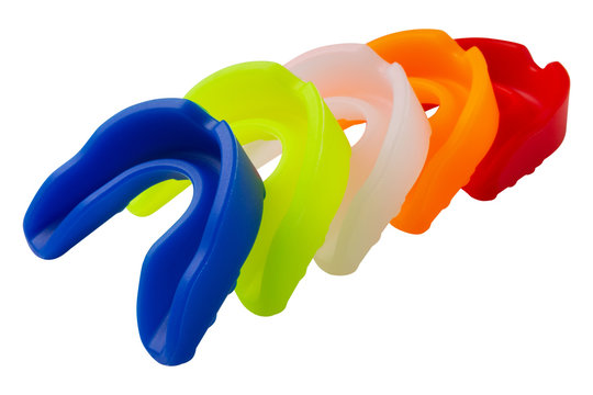 five multi-colored boxing mouth guards for protecting teeth, are stacked, on a white background