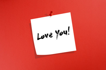 White post it note paper with love you message on red background
