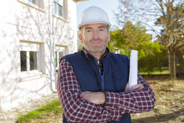 confident male architect wearing hardhat in front of a building