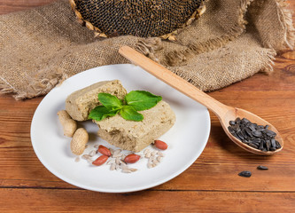 Sunflower halva, sunflower seeds, peanuts against dry ripe sunflower head