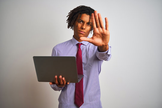 Afro american businessman with dreadlocks using laptop over isolated white background with open hand doing stop sign with serious and confident expression, defense gesture