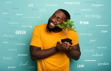 Happy boy hugs a small tree ready to be planted over a light blue color. Concept of forestation,...
