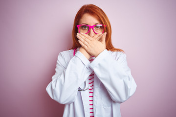 Young redhead doctor woman using stethoscope standing over isolated pink background shocked covering mouth with hands for mistake. Secret concept.
