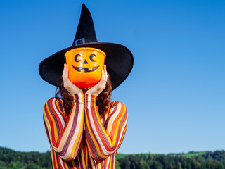 Young woman holding pumpkin bucket for Halloween