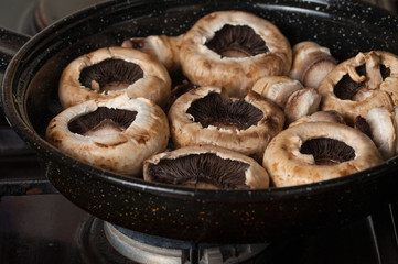 Roasting mushrooms in a black frying pan.Healthy food
