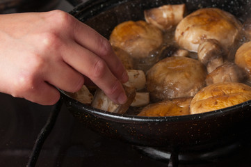 Roasting mushrooms in a black frying pan.Healthy food
