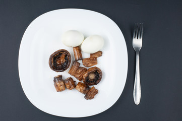 Mushrooms and boiled eggs on a white plate isolated on a black background.Natural food