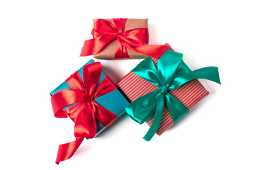 Three natural paper wrapped gift boxes with atlas ribbon bows of traditional colours, isolated on white