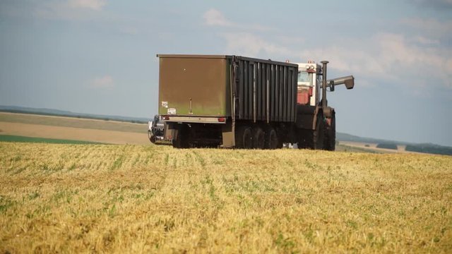 Harvester Pours Grain Into A Truck On The Field. Harvester combine pours the grain into the truck on the field. Threshing machine pouring the just harvested wheat into truck. Food industry concept.