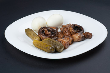 Mushrooms and boiled eggs on a white plate isolated on a black background.Natural food