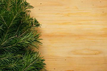 Green fir christmas tree branch on raw wooden background