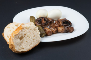 Mushrooms and boiled eggs on a white plate isolated on a black background.Natural food