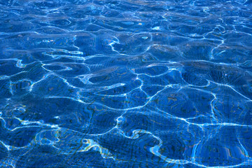 Water in the pool, clear and sea through, bottom of the pool with mosaic and reflections