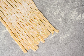 Handmade homemade Italian spaghetti on the kitchen table in flour. Close-up.