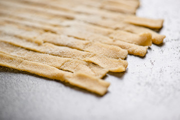 Simple and delicious homemade food. Handmade spaghetti on the kitchen table sprinkled with flour. Close-up.