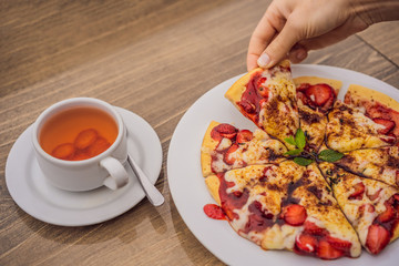 Woman eating delicious strawberry pizza on a balinese tropical nature background. Bali island, Indonesia