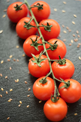 cherry tomatoes on a branch top view on a dark background with flax seeds