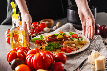 Italian traditional cuisine. Plate of delicious pasta with tomatoes on the kitchen table. Close-up.
