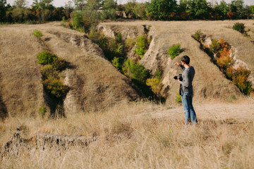 wedding photographer takes pictures of the bride and groom in nature in autumn, the photographer in action
