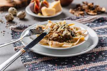 Plate of delicious homemade pasta with mushrooms and parmesan on a rustic napkin. Close-up.