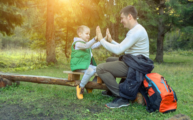 Happy father and son hikers traveler siting in wood around mount