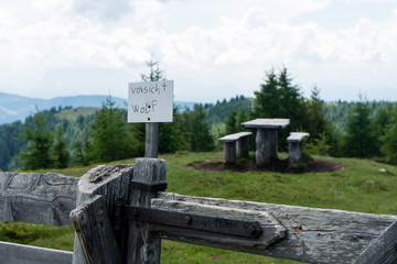 handgeschriebenes Vorsicht Wolf Schild auf einem Holzzaun mit Bank und Tisch im Hintergrund