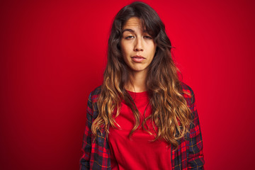 Young beautiful woman wearing casual jacket standing over red isolated background looking surprised and shocked doing ok approval symbol with fingers. Crazy expression