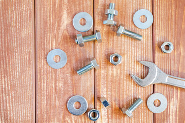 Metal bolts and nuts on vintage wooden background with adjustable wrench