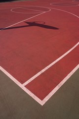     basketball hoop shadow silhouette on the red court on the street