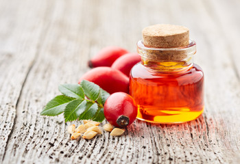 Rose hips oil on wooden background