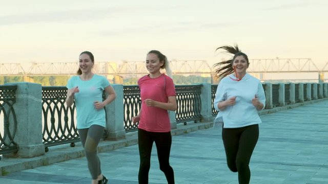Slow motion shot of three girls girlfriends morning run on the promenade