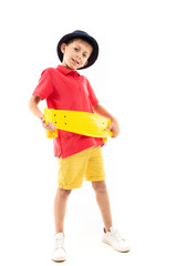 A little boy in panama, yellow jersey, red shorts and white sneakers stands and holds a yellow penny in his hands