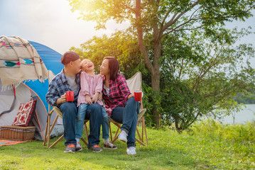 Group of asian family travel and camping at lakeside in forest ,sitting all  together and smile. Family and outdoor activity concept.