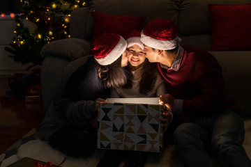 Happy family portrait, father mother and daughter, celebrate Christmas and New Year together, opening gift box with magically surprise