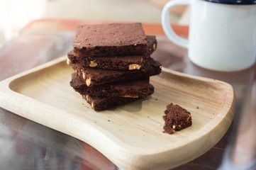 Piece of stack dark chocolate brownies on wooden plate.