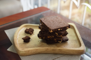Piece of stack dark chocolate brownies on wooden plate.