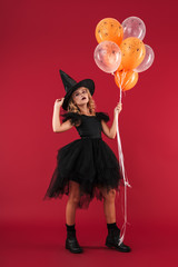 Witch in carnival halloween costume holding balloons