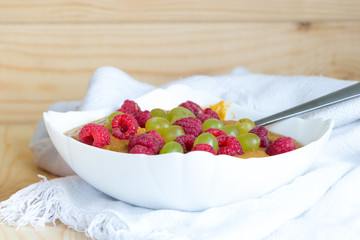 Delicious healthy raw food diet breakfast. Vegan flax porridge with raspberry and grape raisins in white bowl with spoon on linen fabric. Close-up. Yummy and harmless nutrition concept. Copy space
