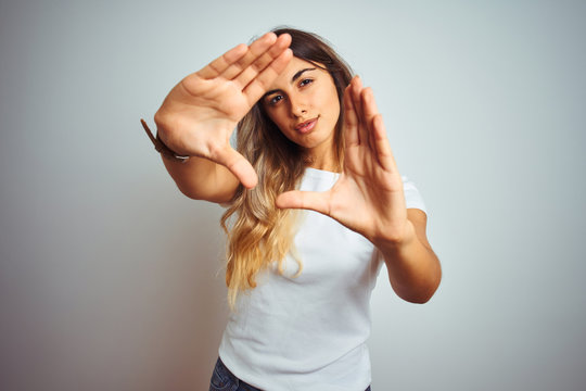 Young beautiful woman wearing casual white t-shirt over isolated background doing frame using hands palms and fingers, camera perspective